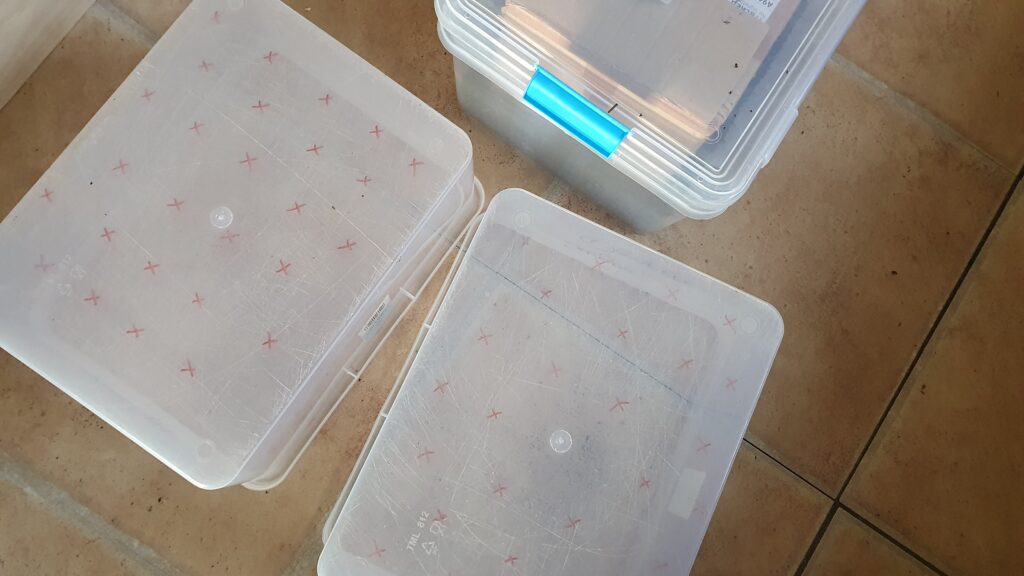 Upturned plastic boxes with red x marks where holes will go