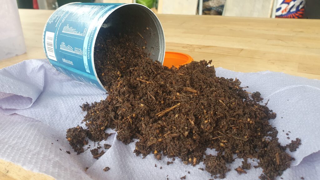 An upturned container spills soil out onto a blue cloth