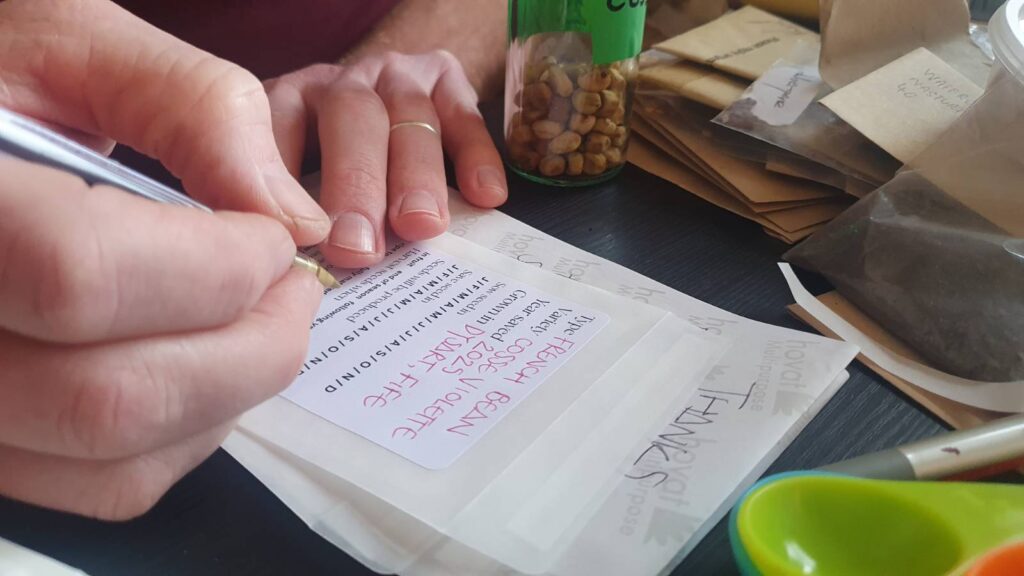 A hand writing on a seed packet.
