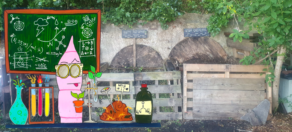 A worm with goggles and test tubes in front of some compost bays